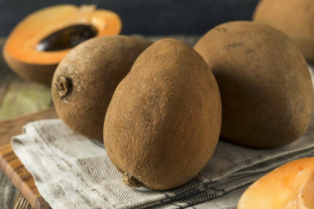 Whole and half pieces of mamey sapote fruit.
